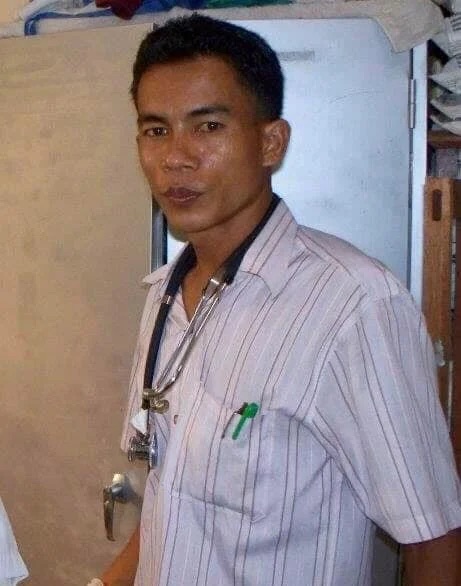 A doctor and a family member standing beside Sok Chorn's hospital bed.