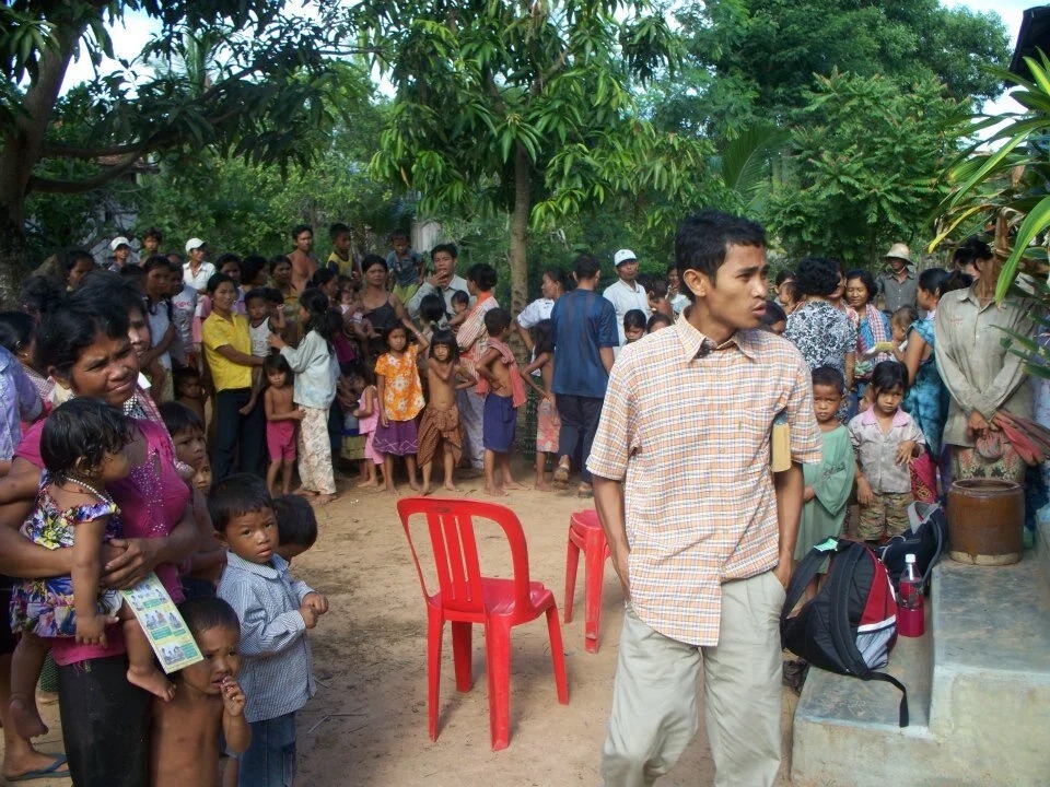 Villagers queuing outside the clinic, with a staff member managing the line.
