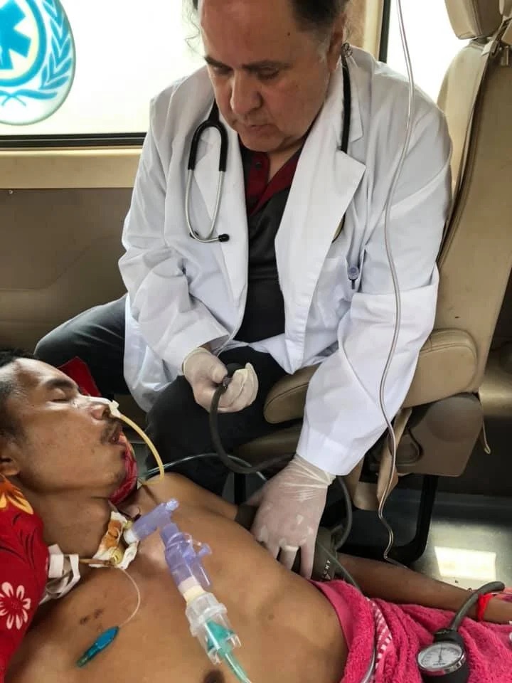 Medical staff moving Sok Chorn on a stretcher into an ambulance.