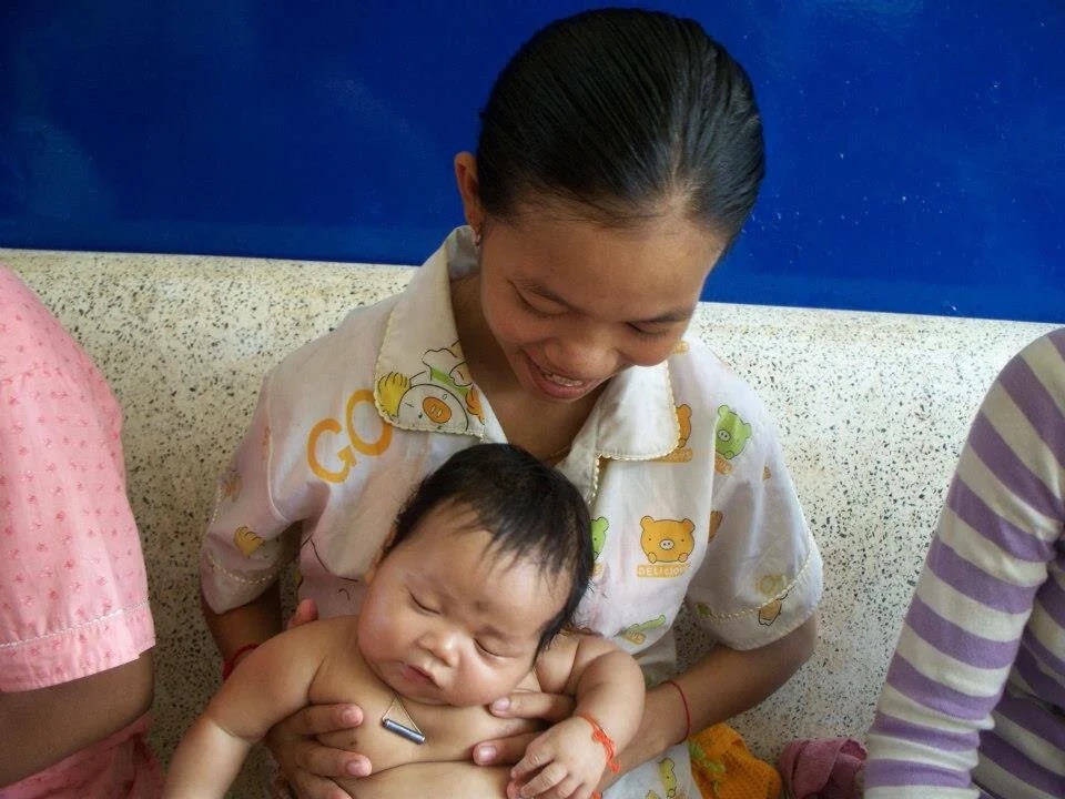 A large crowd of villagers waiting under the clinic's covered entrance.
