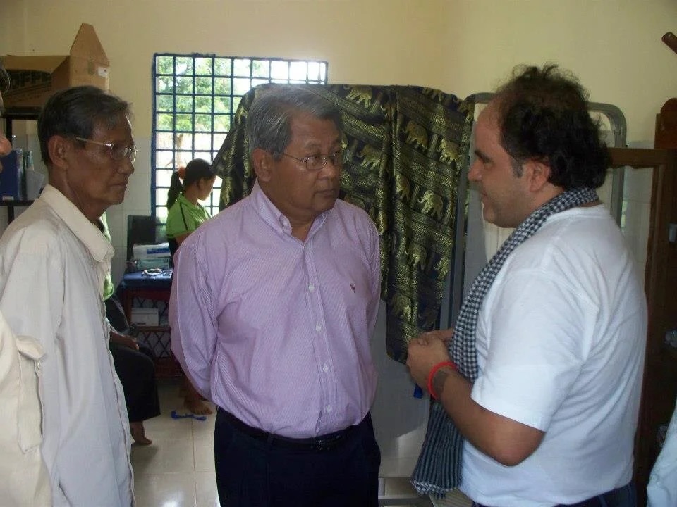 James Garcia in conversation with two Cambodian health officials inside a clinic.